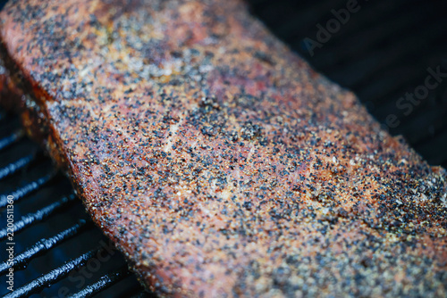 Barbecue pork ribs seasoned with salt, pepper, garlic for a crunchy bark. The bbq meat is cooking on a pellet grill smoker. 