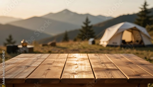 A sturdy wooden table overlooks a scenic mountain campsite at sunset.