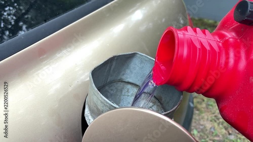 Refueling filling car benzine gasoline fuel at gas station from canister,funnel into automobile's tank,petrol prices.Gasoline, petroleum.