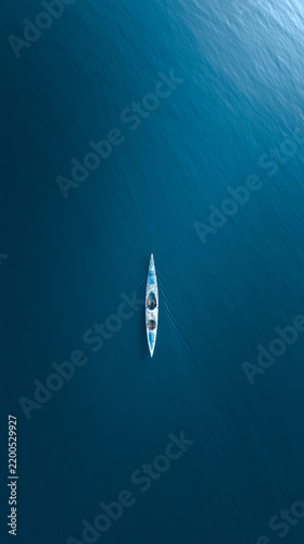 Minimalist lone kayak on calm lake with cold cyan blue lighting drone aerial