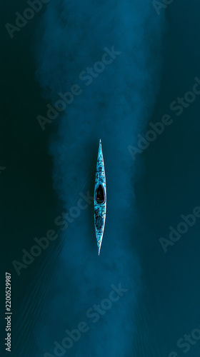 Minimalist lone kayak on calm lake with cold cyan blue lighting drone aerial