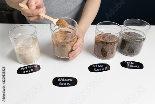 Scooping high fiber ingredients into a glass jar on a clean white kitchen counter