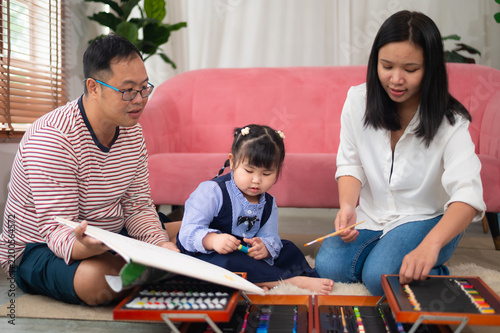 A joyful family spending quality time together, engaged in creative activities. The parents and their child explore art and expression in a cozy home setting.