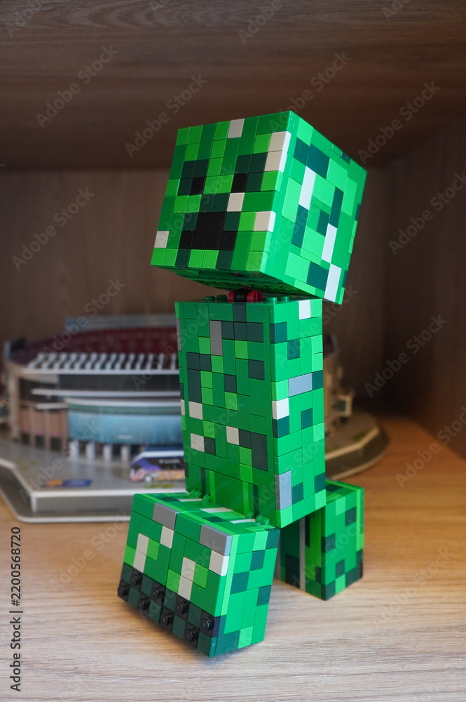 Obraz premium A green blocky Creeper character figure built from plastic construction bricks on a wooden shelf