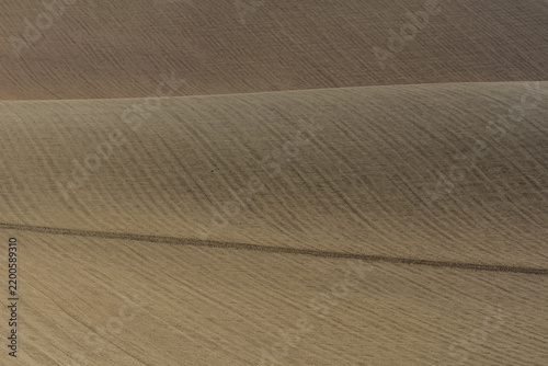 View of rolling plowed fields with soft curves and textured soil in Corridonia, Marche, Italy.