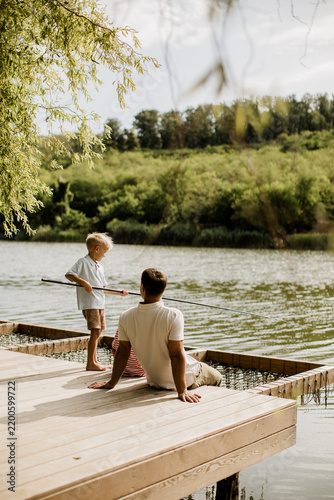 Father and son enjoy a peaceful fishing moment by the riverbank
