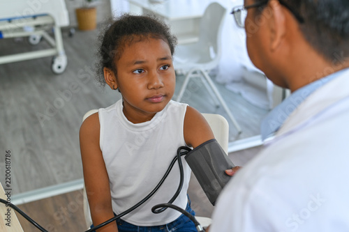 Картината върху платно A young girl receives a blood pressure check from a healthcare professional in a modern medical setting, promoting the importance of health monitoring