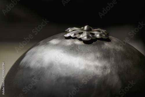 Detail of a metal flower on the top part of a metal helmet.