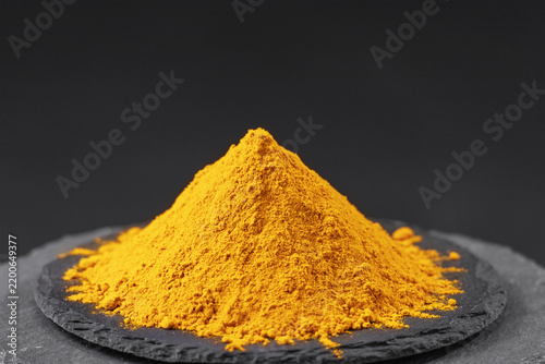 dried turmeric root powder or curcuma longa on a black slate stone tray
