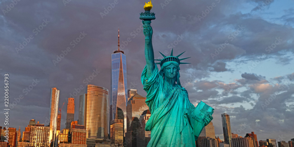 Fototapeta premium Liberty monument. Liberty statue before New York City skyline. Iconic America symbol. New York City skyline. Famous USA symbol in NYC. Statue of Liberty in New York City.