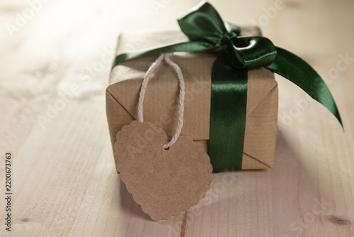 a mock-up of a gift with a green bow and a blank brown heart-shaped label