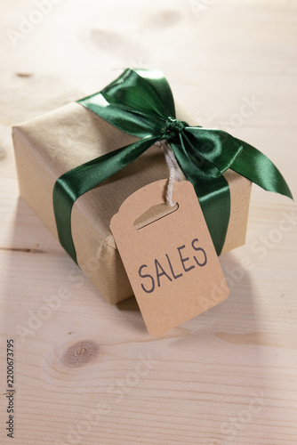 gift with a green bow and a brown label bearing the English word ‘sales’
