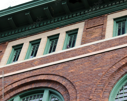 Fotografie Low-angle architectural view of brick building with mourning dove resting on win