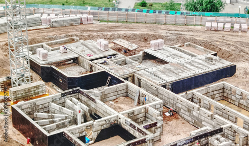 Aerial View of Concrete Foundation Construction Site With Workers and Crane at Urban Development.