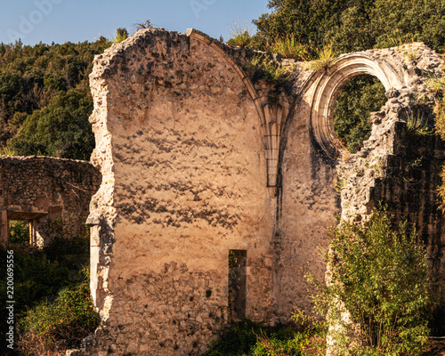 Ancient monastery ruins with gothic rosette and arch in sunlight.