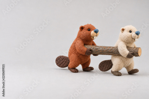 Two felt beaver toys carry a wooden log together. Space for text.