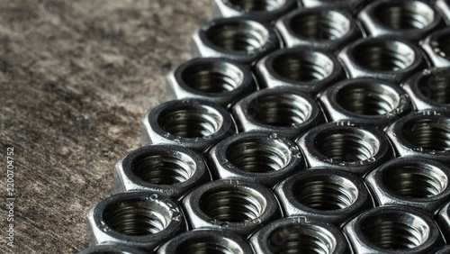 Fotografie Group of metallic hex nuts creating a textured pattern, representing industrial