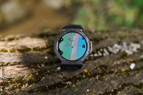 Rugged smartwatch with GPS navigation map lying on a mossy stone outdoors