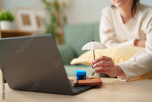 Foto Woman holding a miniature umbrella over travel essentials beside a laptop, trave