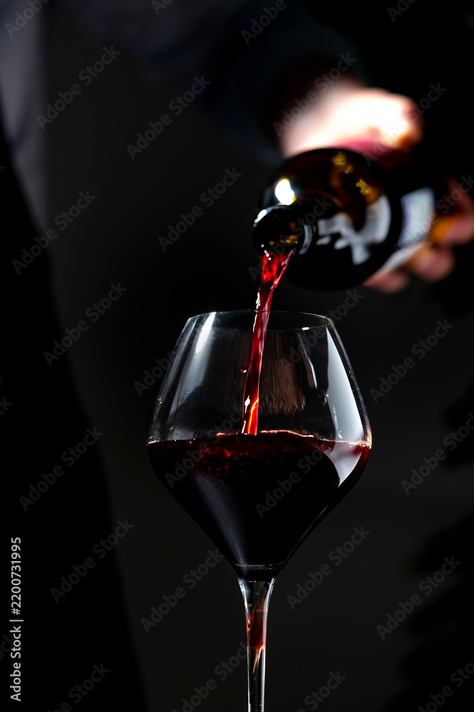 Obraz premium Rich Cabernet Sauvignon red wine in glass — professional tasting session. Restaurant sommelier with open bottle pouring alcoholic drink. Exclusive catering service, gourmet fine dining event.
