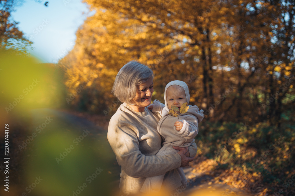 Obraz premium Grandmother kissing baby outdoors in autumn nature.