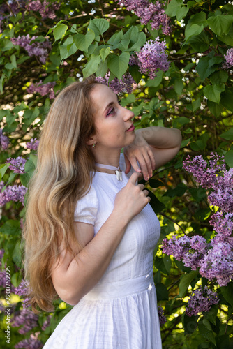 Soft feminine portrait with blooming lilac bouquet and natural sunlight