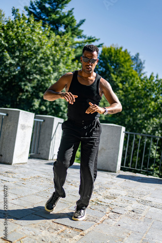 Fotografie Black man dancing with expressive hand gestures and energetic movement, portrayi
