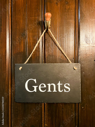 A slate door string hanging via string and a hook on the back a of a gent's toilet door