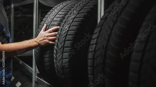 Tire at repairing service garage. Technician man replacing winter and summer tyre for safety road trip.