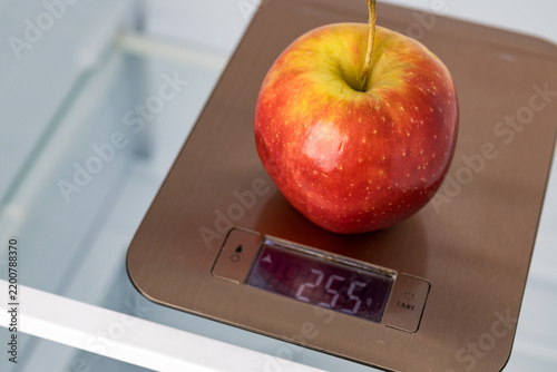Apple weighing on kitchen scales in empty refrigerator