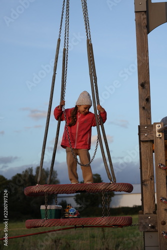 Konstfotografi Young girl playing on a playground rope swing structure outdoors at sunset
