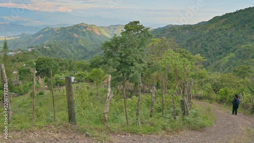 Hiker Walking Along Winding Mountain Trail Through Lush Countryside With Panoramic Valley Views