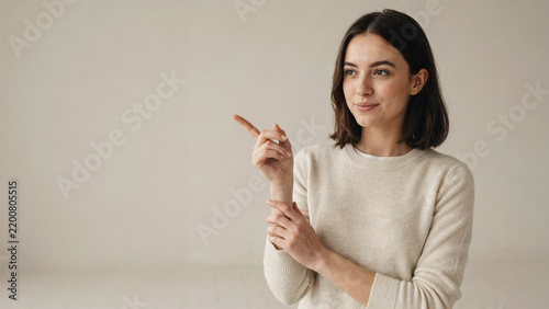 Young professional woman pointing to the right with copy space in neutral studio lighting