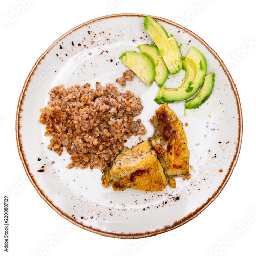 Obraz na plátně Tender meat of fried chicken meat is garnished with boiled buckwheat, complemented by avocado slices