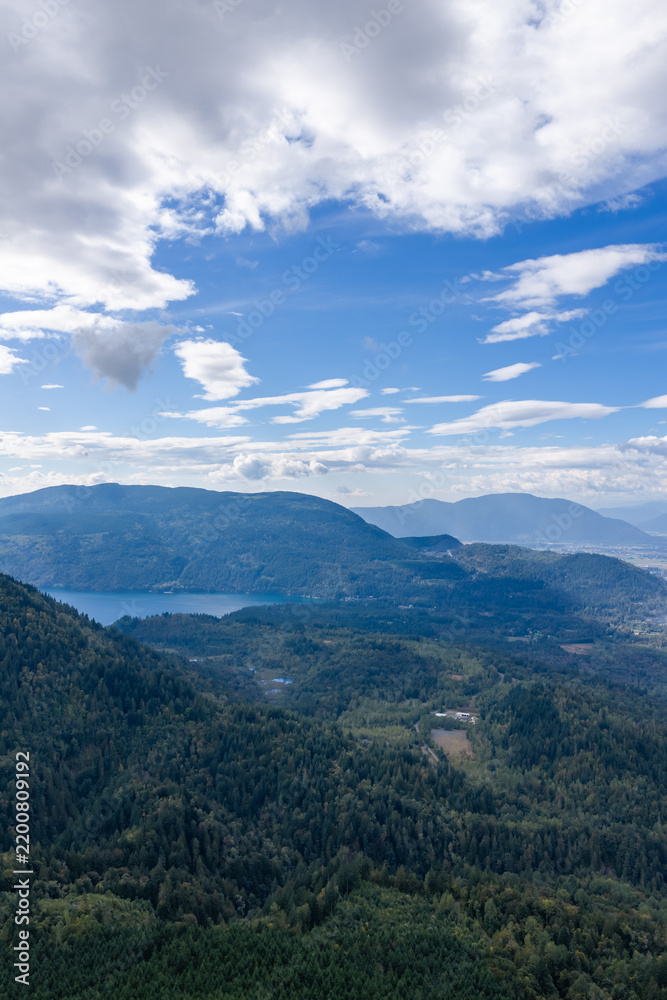 Fototapeta premium Blue Sky Over Forested Mountains and Lake Near Chilliwack BC Canada With Puffy Clouds