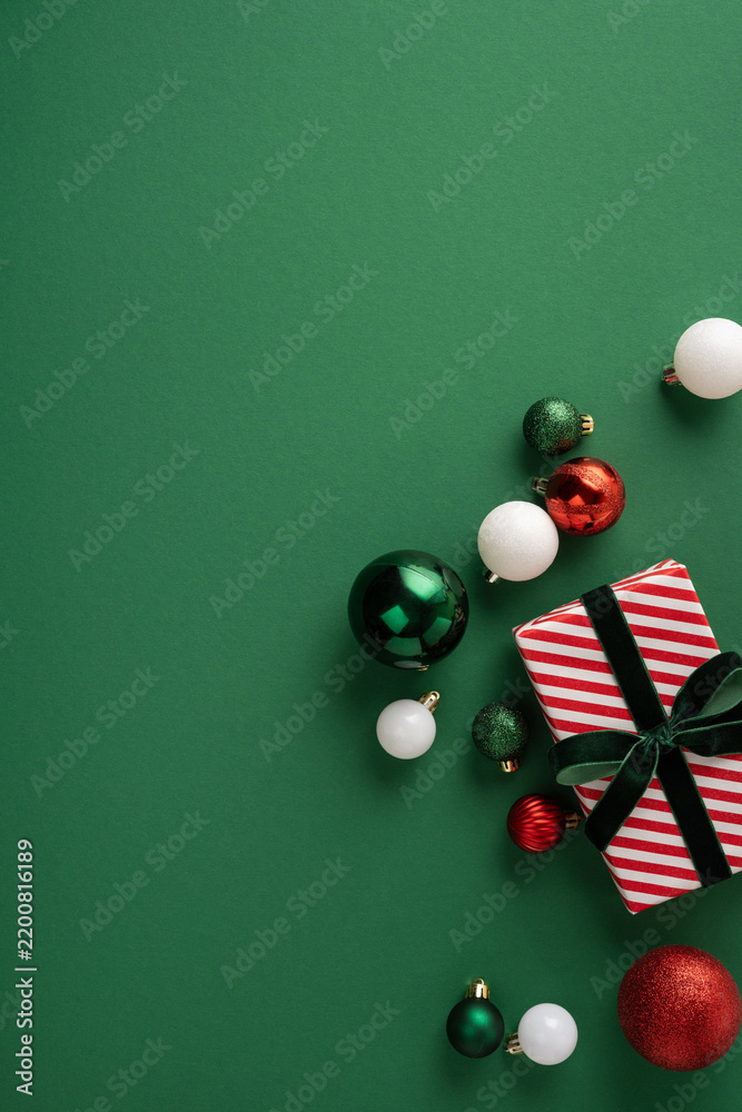 Obraz premium Festive Christmas gift and ornaments with striped wrapping and baubles for Merry New Year celebration on vertical green blank space