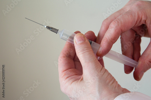 Woman is holding a big syringe
