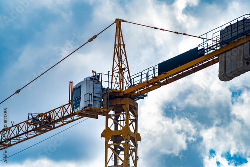 Картината върху платно A massive yellow tower crane operating under a bright, cloudy sky