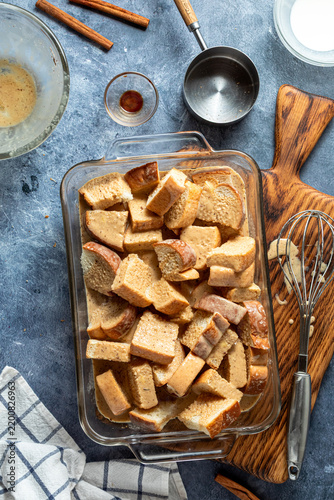 A glass baking dish filled with custard soaking bread cubes ready for baking.