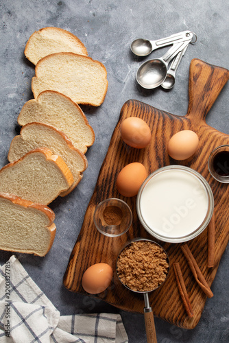 Ingredients on an beside a wooden cutting board for making French toast.