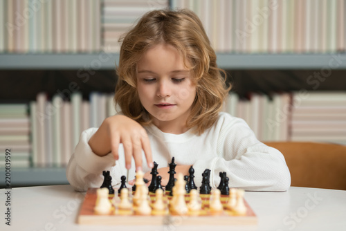 Child playing chess. Kids early development. Boy kid playing chess at home. Portrait close up, funny face. Clever kid thinking about chess.
