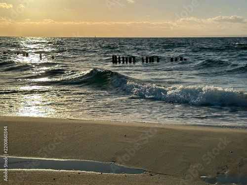 Cuadro en lienzo Golden sunlight reflected in the sea beyond a line of old wooden posts