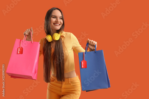 Young woman with shopping bags on orange background. Black Friday Sale