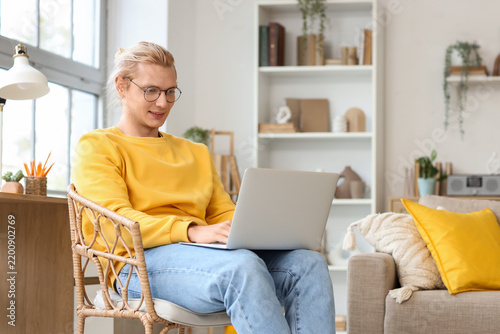 Young man working with laptop in chair at home