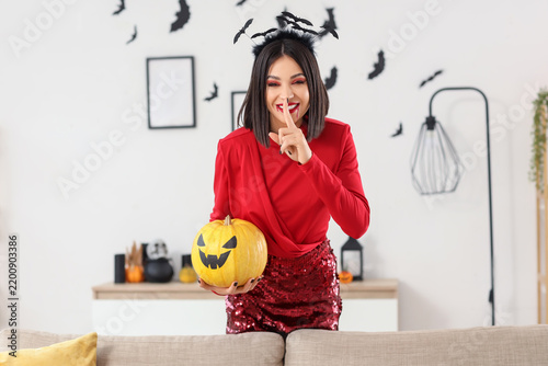 Beautiful young happy woman dressed for Halloween with pumpkin showing silent...