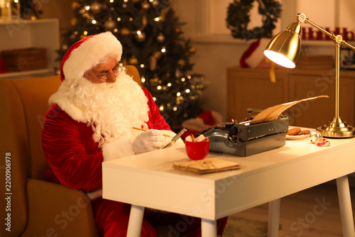 Santa Claus with typewriter taking notes while writing Christmas story at night