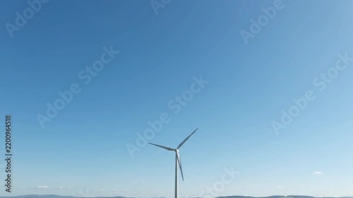 White wind turbine generating clean renewable energy against a clear blue sky
