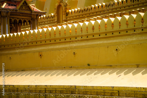 Pha That Luang, Golden lao temple wall with ornate traditional architecture.