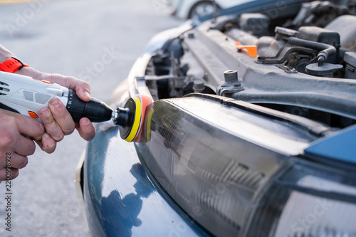 The process of polishing car headlights outdoors. 