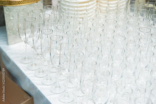 Rows of empty glass flutes arranged on white tablecloth near plates